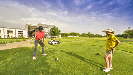 guests playing golf at Karma Lakelands with a building in the background.
