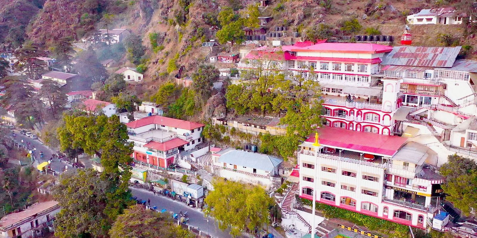 Aerial view of Mussoorie with buildings and trees around it.