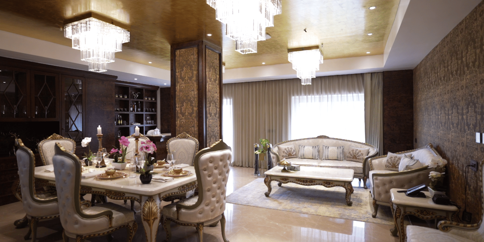 Opulent interior featuring a lavish dining area with gold-accented chairs and a classic, brightly lit chandelier.