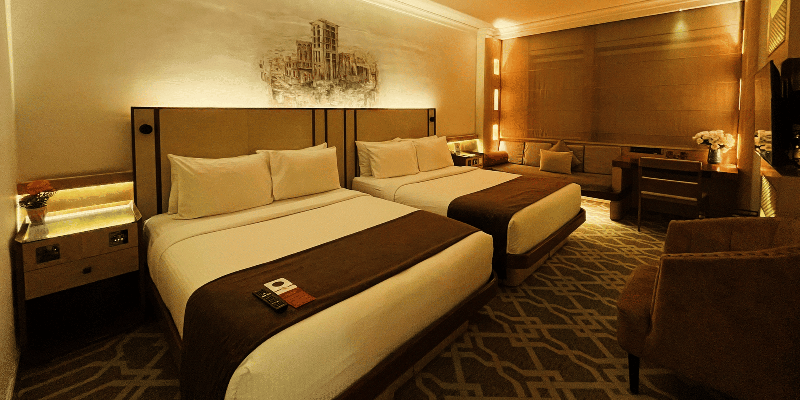 Wide shot showing two twin beds and a bedside table in a room at Marco Polo Hotel.