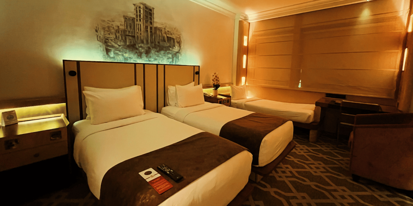 Two twin beds and a seating area and a single bed at the side of the room at Marco Polo Hotel.