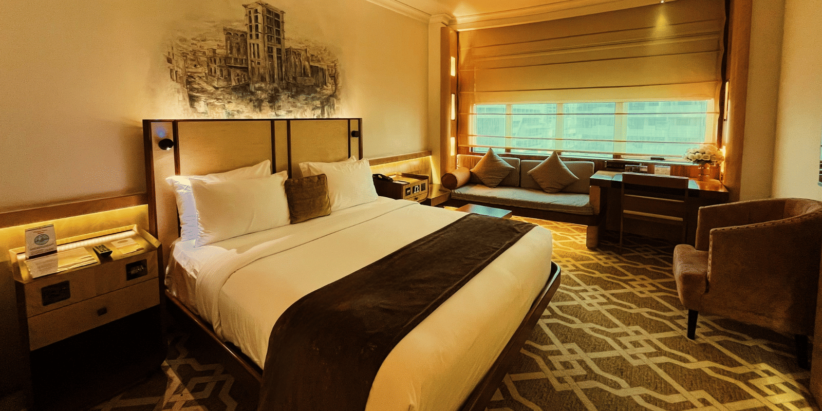 Hotel room with bed, sofa, and window view at Marco Polo Hotel.