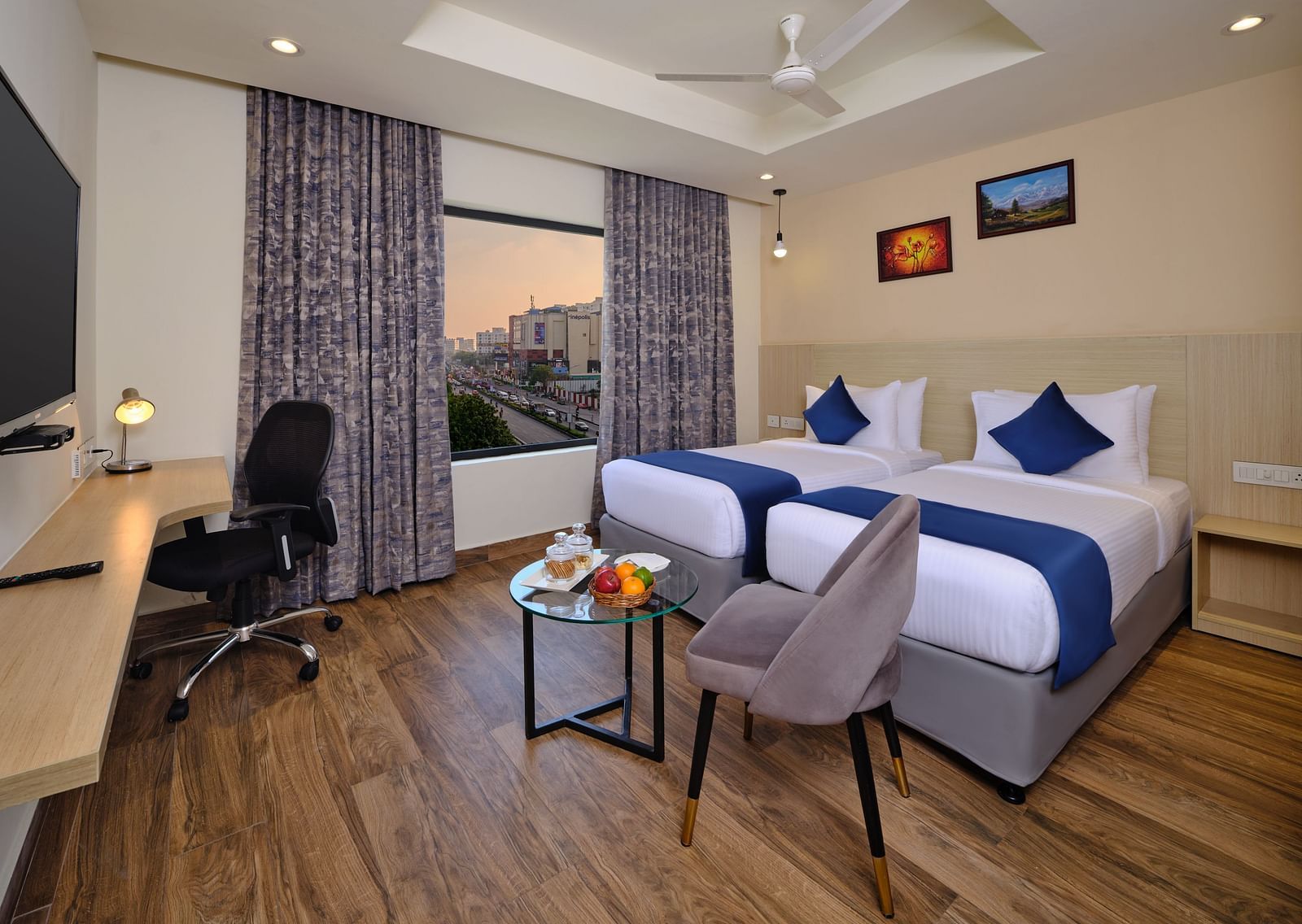 A room at Essentia Premier Hotel, Chennai with twin beds, a television and work desk and chair