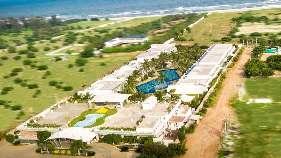 An aerial view of a resort complex with multiple white buildings and swimming pools along a coastline | Grand Bay Resort and Spa