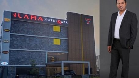 A man in a suit standing in front of the ILARA Hotel building, posing confidently.