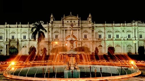 a brown coloured palace with a water fountain in front of it