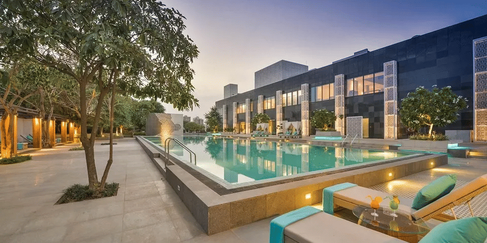 Outdoor poolside seating area with trees and lights near the building at Karma Chalets during dusk.