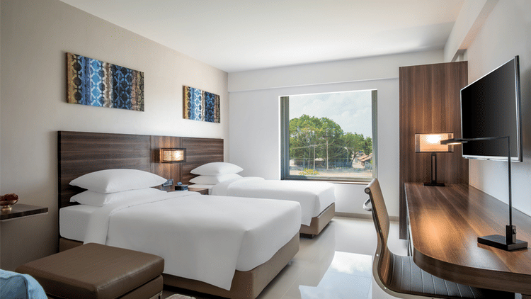 Standard twin room decked with two beds, television and a working desk at The Residency Towers Rameswaram