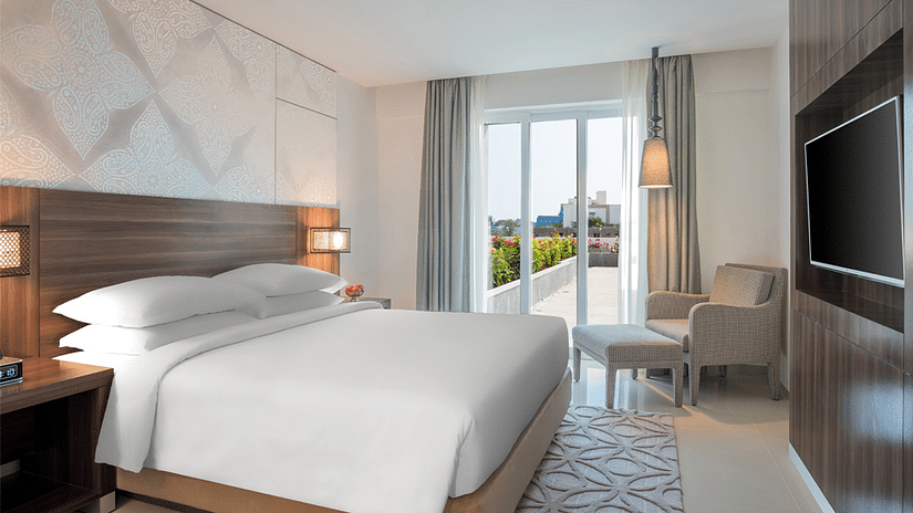 King Room with a balcony decked with a plush bed, couch and television at The Residency Towers Rameswaram