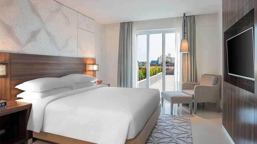 King Room with a balcony decked with a plush bed, couch and television at The Residency Towers Rameswaram