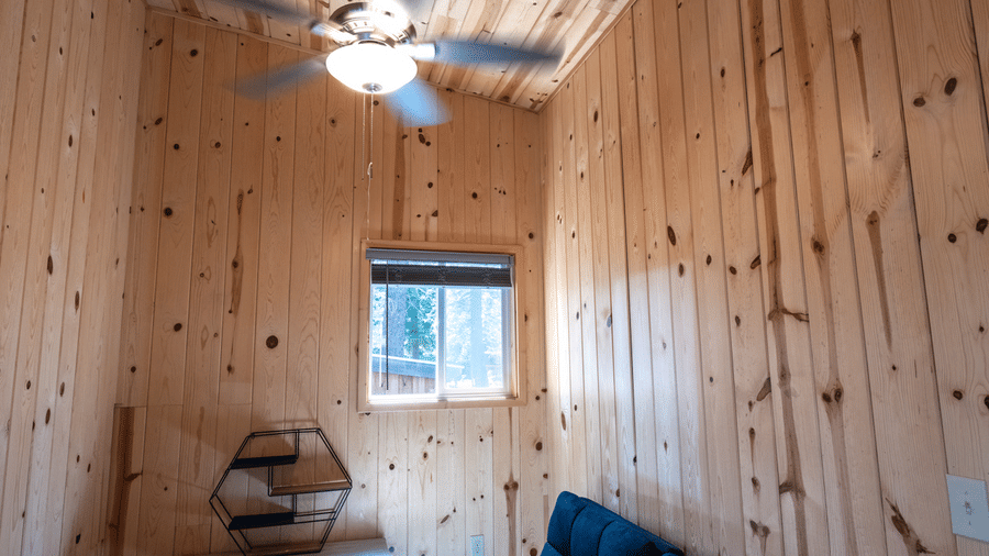 A sitting area at Kit Carson Lodge with a cushioned sofa, wooden side table, and a window allowing natural light into the space