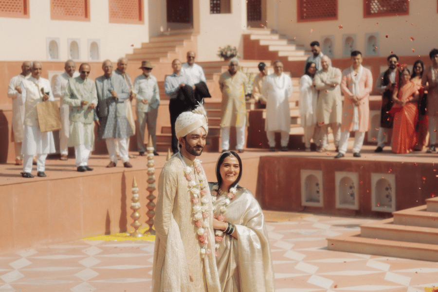 Bride and groom standing together on a yellow and orange floral rangoli in the courtyard at Umaid Palace.