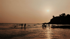 Silhouettes of people playing in the surf at sunset on a beach in Goa.