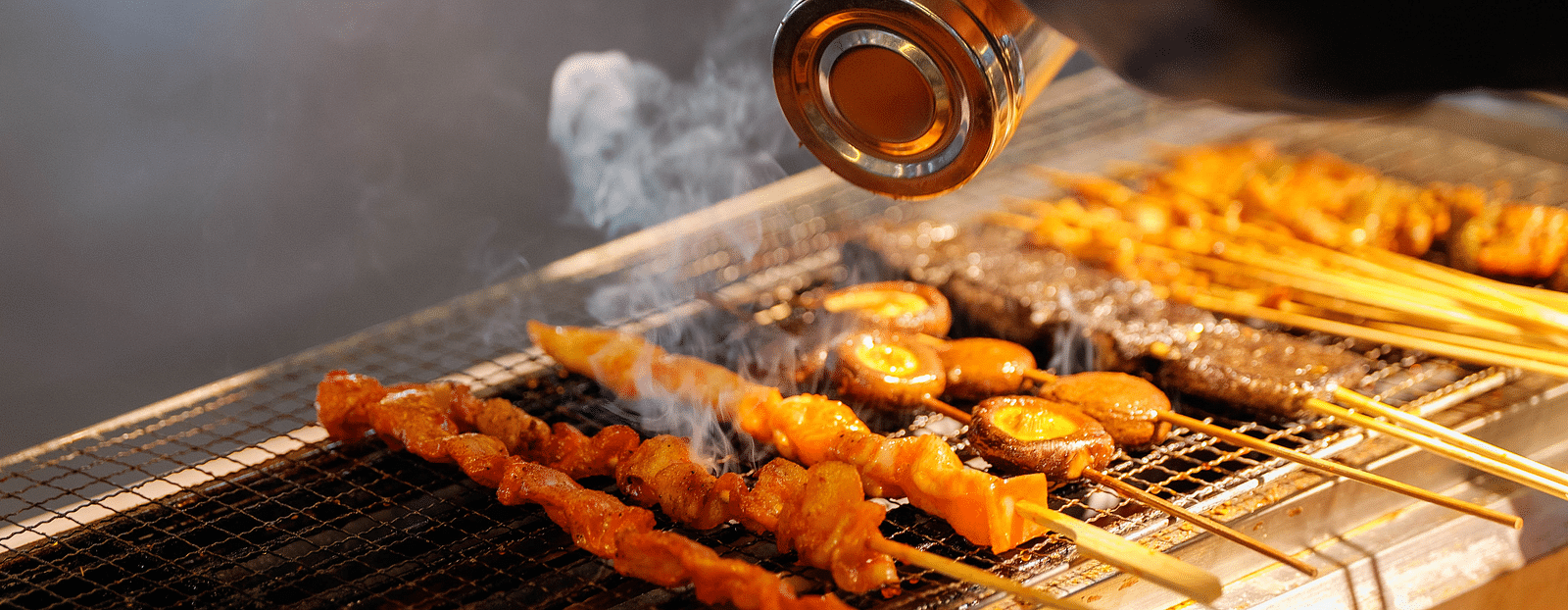 a person seasoning food being cooked on a grill