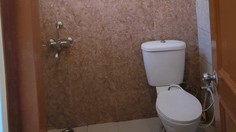  Compact bathroom with a toilet, wall mounted water heater, wash area and tiled walls.