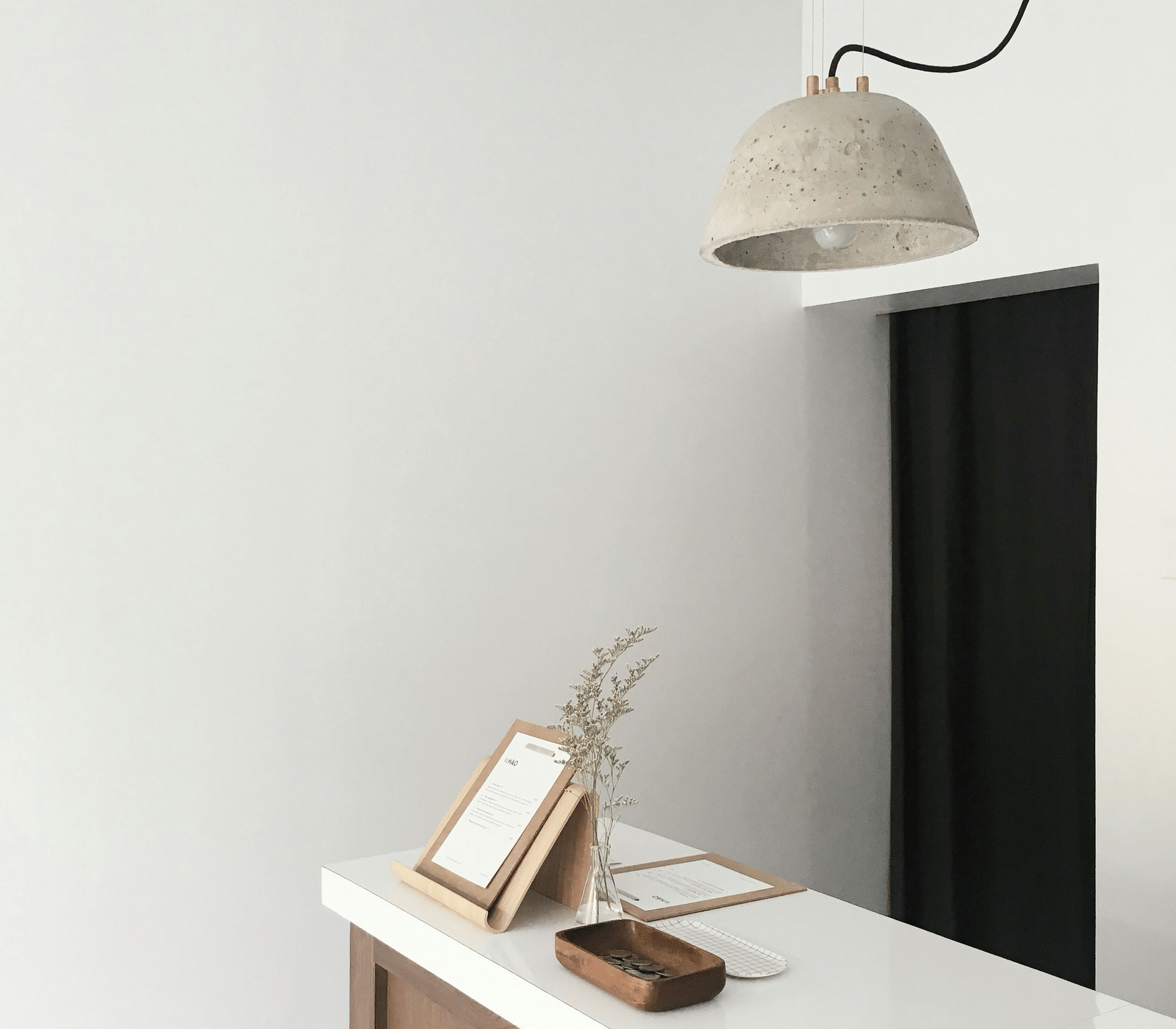 A minimalist interior showing a white wall, a mounted television, a white console table, and a modern pendant lamp.