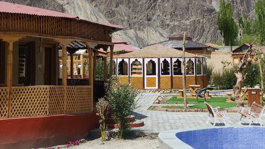 A partial view of the White Sands Resort,Ladakh highlighting the building's design and a swimming pool area with mountains in the distance.