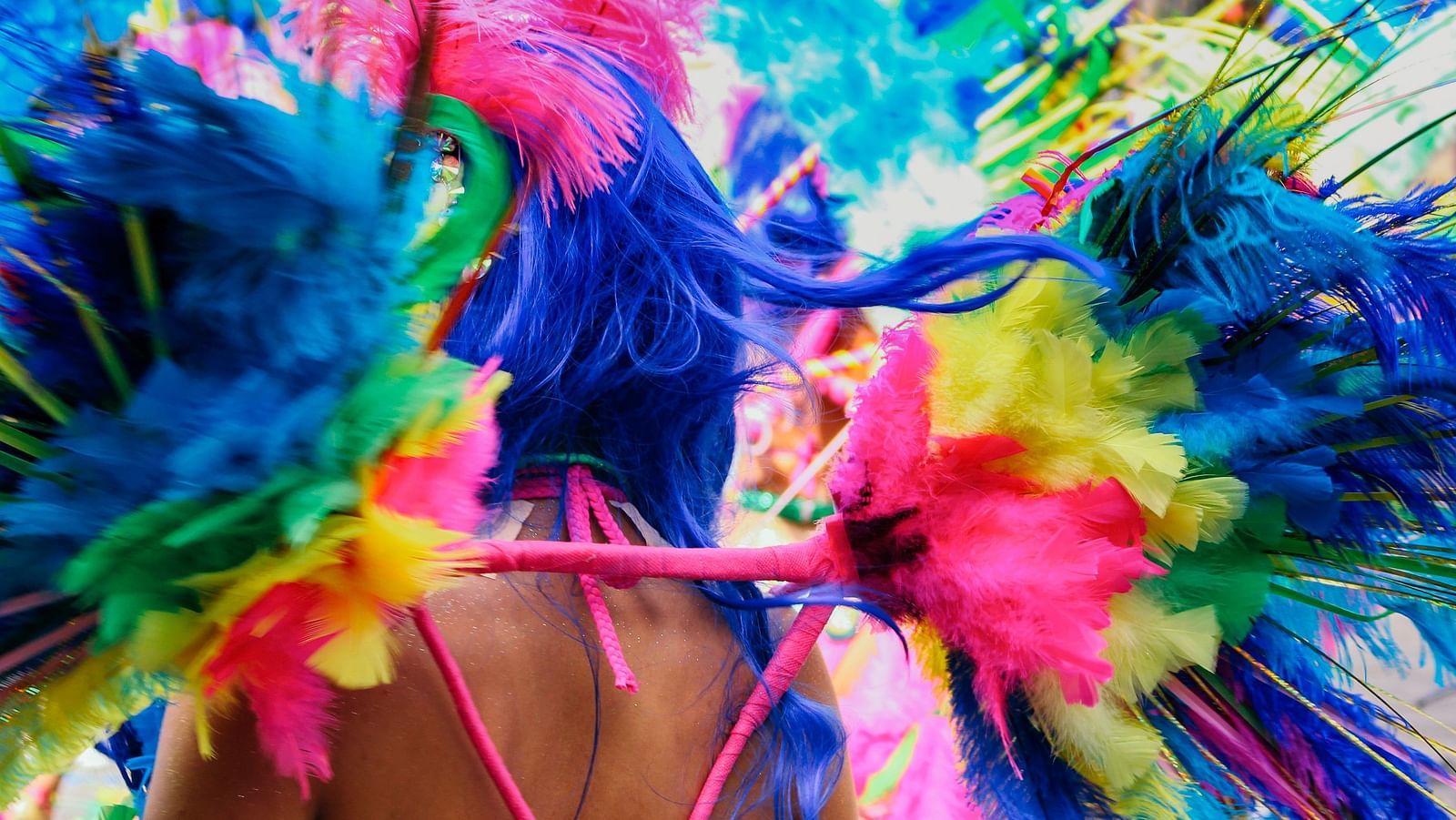 A woman having decorative feathers attached to her clothes during a carnival.