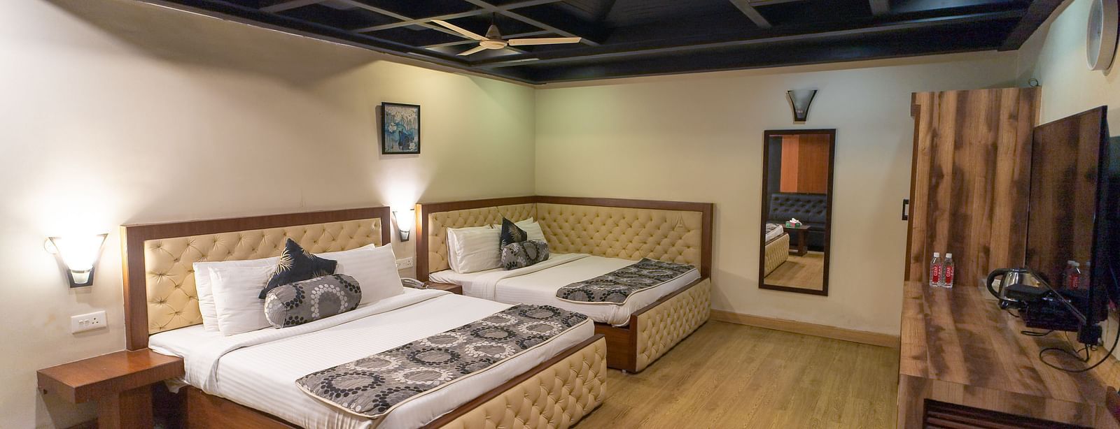 Family Room featuring two large beds, desk, and wooden wall paneling. - Hotel Ashok Nagpur