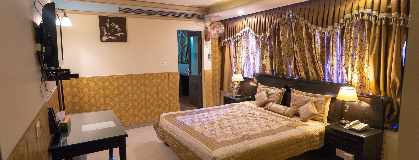 Queen Room featuring a bed, a desk, and a television. - Hotel Ashok Nagpur
