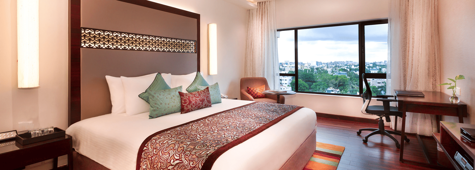 A spacious, well-lit hotel room at GRT Grand Chennai with a king sized bed and a large window overlooking the city. - Best hotel near U.S Consulate Chennai 