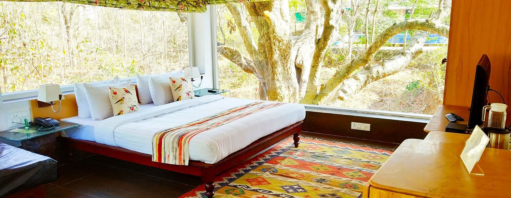 A full view of Tree house with a bed and glass windows | The Riverwood Forest Retreat, Pench