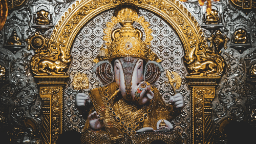 A statue of Ganesha with decorative elements, ornate carvings, and detailed background patterns.