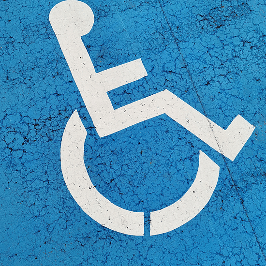 A white wheelchair symbol is painted on a blue textured surface.