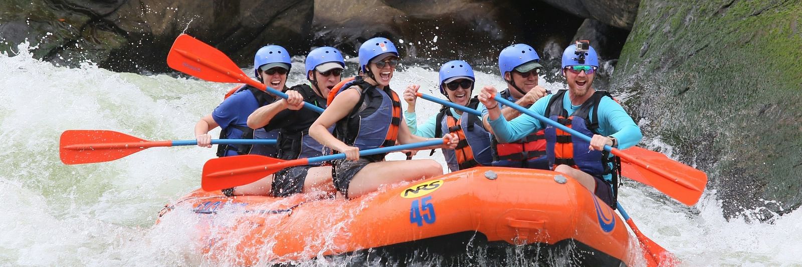 Front view of a river rafting group rafting in an orange boat