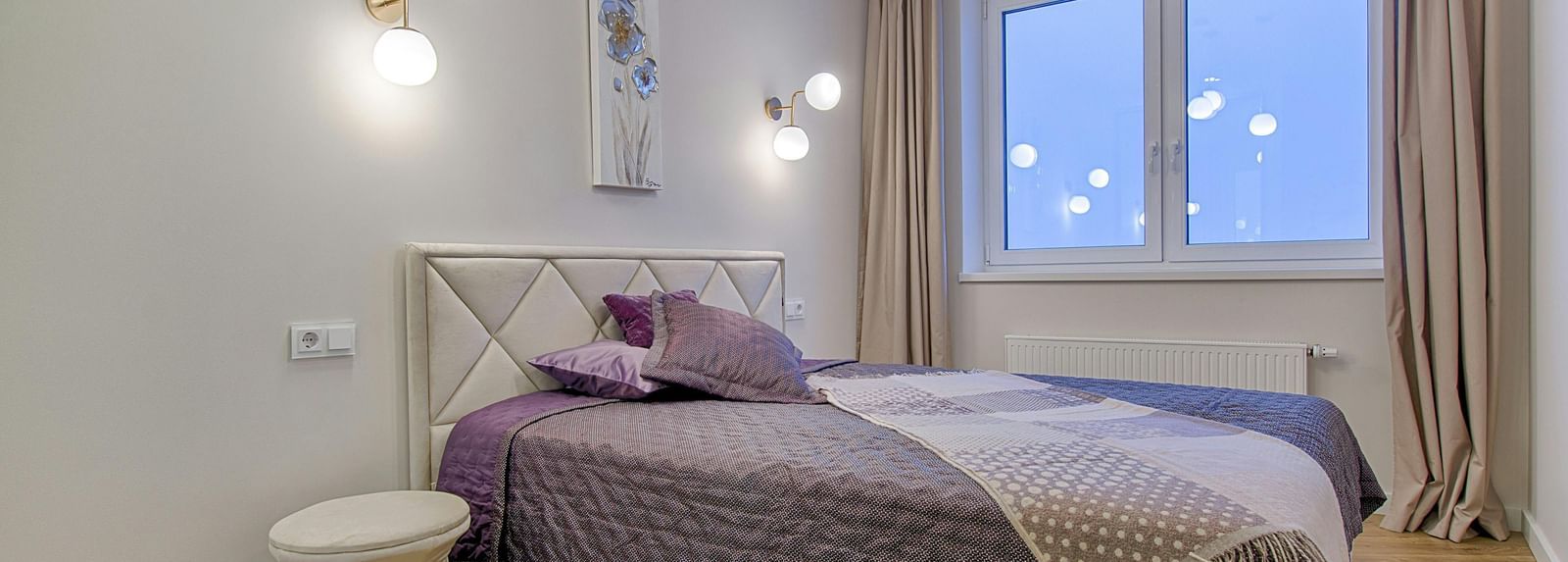 A modern bedroom with a double bed, light walls, and minimalist furniture.