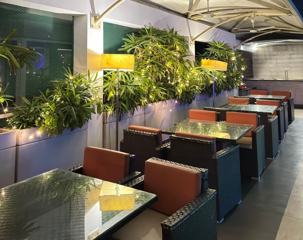 Dining area with tables, chairs, and potted plants at the side of Cenneys Gateway.