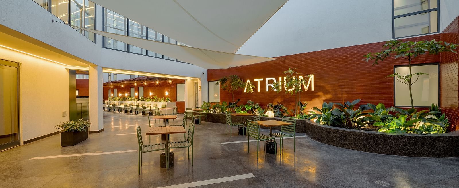 A modern outdoor seating area with a large, red 'ATRIUM' sign on the wall.  - The Pelican Hotel, Accra