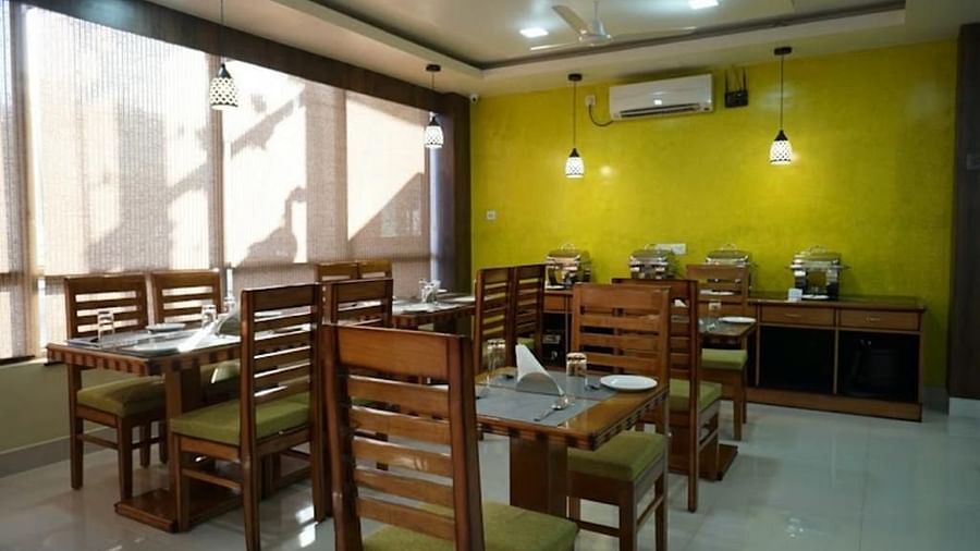 A well-lit dining area with wooden furniture and vibrant green walls, perfect for relaxed meals - Pemaling Lords Eco Inn Guwahati