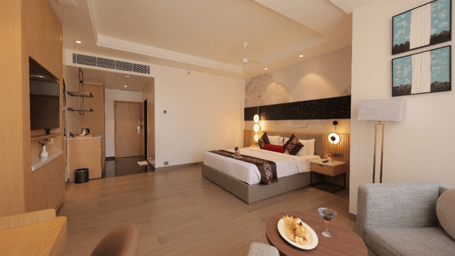 Spacious guest room at Lords Inn Somnath with a comfortable bed, wooden flooring, seating area, bedside tables, warm lighting and contemporary interiors.