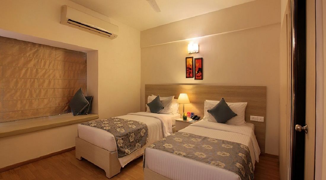 Premium room at Starlit Suites, Bangalore with twin beds with a lamp on the nightstand in the middle