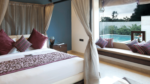Interior view of a room at The Serai Chikmagalur featuring a plush bed placed next to a window with pool view