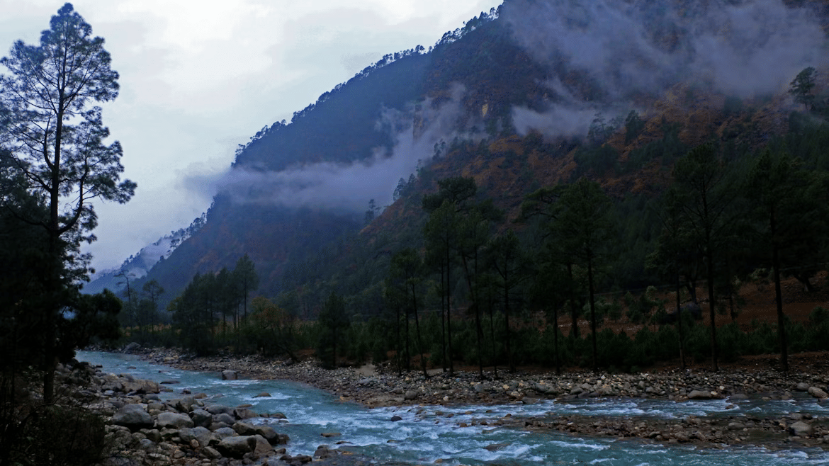 A valley in Dehradun with cloudy sky, mountains, and greenery