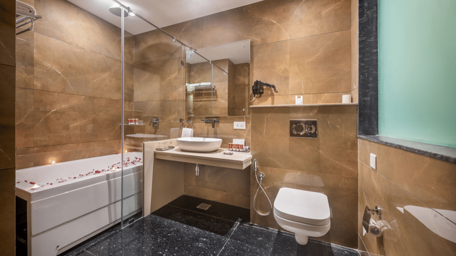 luxurious bathroom with marble tile walls, a glass-enclosed shower, a toilet, and a wide vanity mirror.