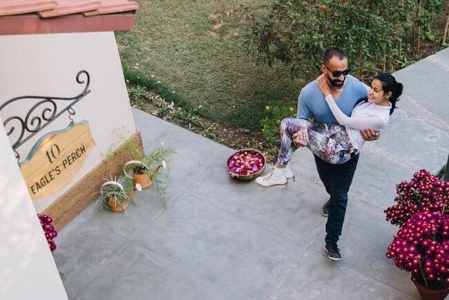 Two people standing and on a paved outdoor walkway near pink flowers and a villa at Karma Chalets.