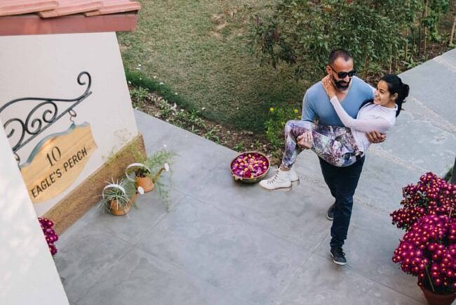 Two people standing and on a paved outdoor walkway near pink flowers and a villa at Karma Chalets.