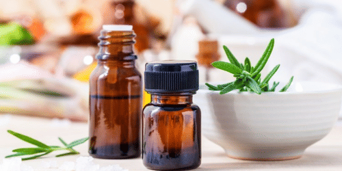 Small bottles placed on a table with a bowl and plant leaves arranged beside them