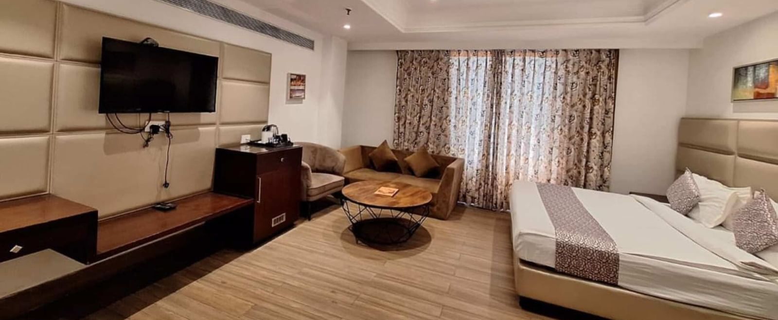 Spacious room at BluSalzz Select - City Centre, Amritsar with sofa seating, TV, and large windows with curtains.