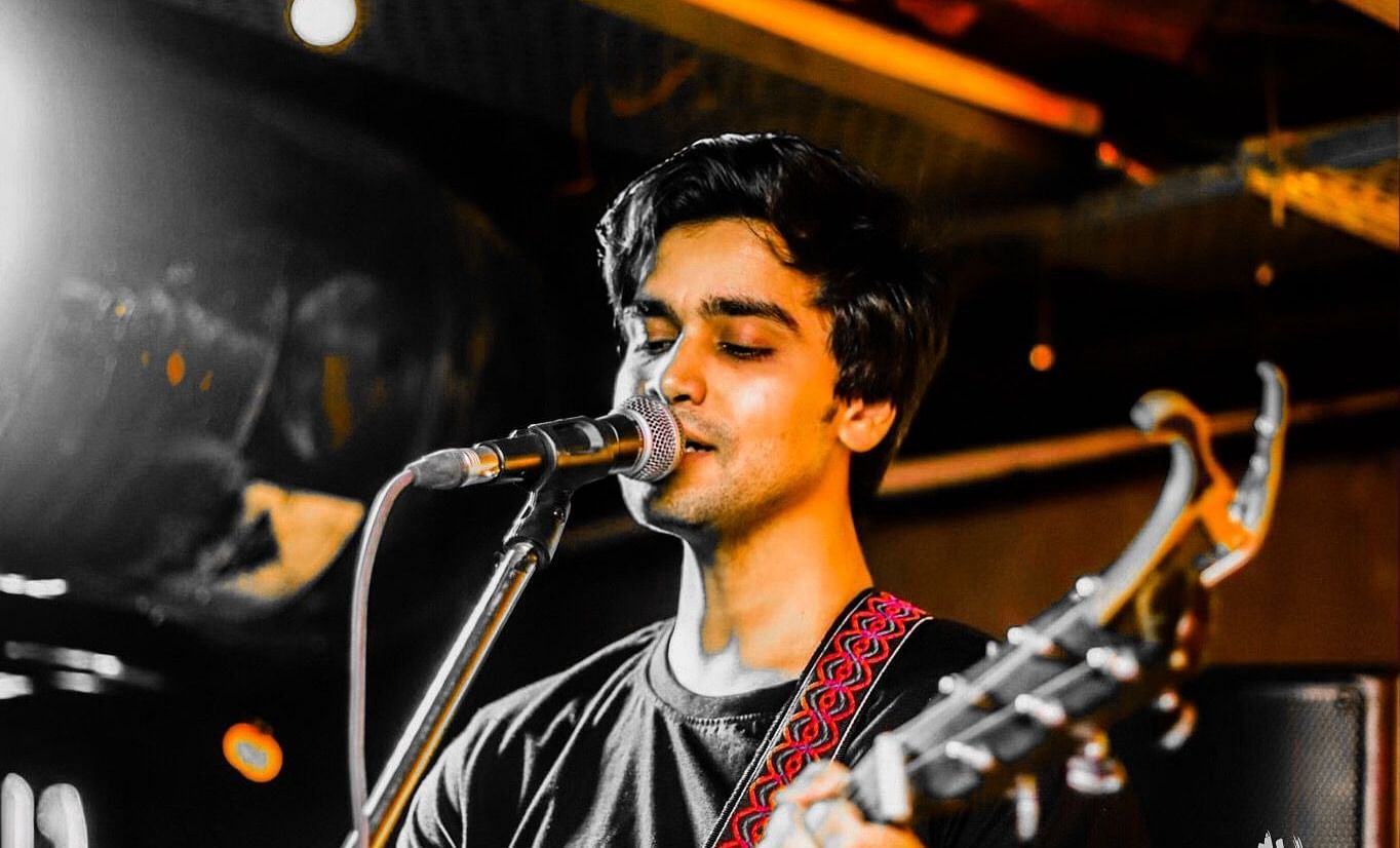 Musician performing live at Ruin Pub by Imperfecto, playing guitar and singing with selective colour effect.