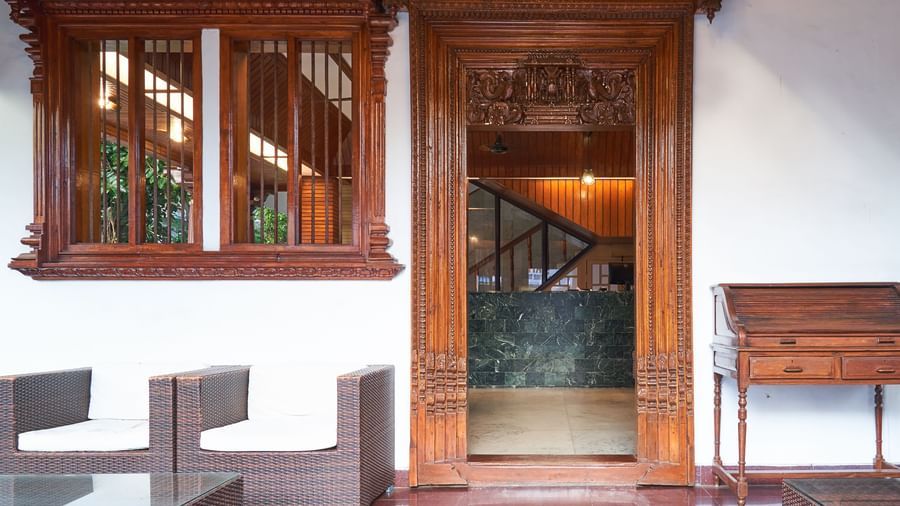 A richly detailed traditional wooden entrance or doorway at Hotel Mamallaa Heritage, with carved accents and stone flooring, possibly leading to a guest room or common area.