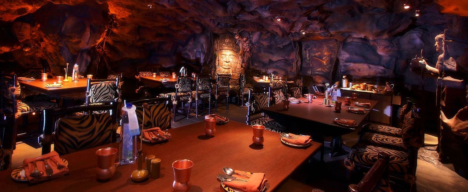 An image of cave themed restaurant with a few sets of chairs and table - The President Hotel Jayanagar Bangalore