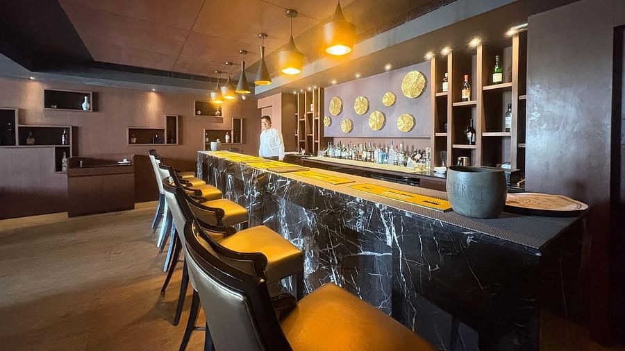 A bar with a dark, textured counter and yellow-toned bar stools, focusing on the bar's design elements and lighting.
