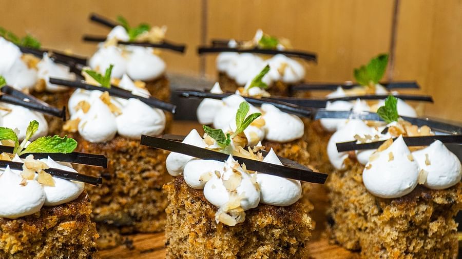 Platter of small cakes topped with cream and garnished with herbs.