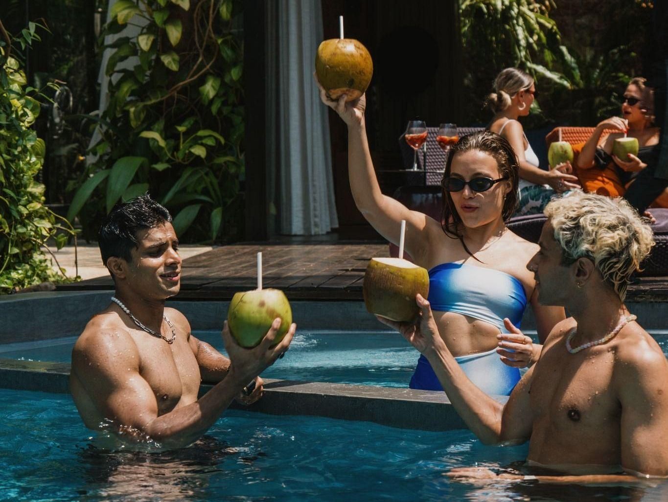 An image of three people enjoying in a swimming pool and sipping fresh coconut water