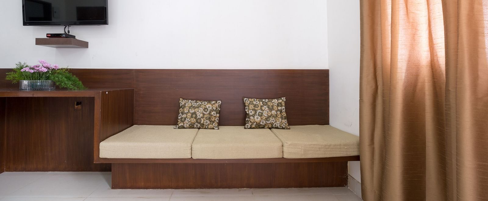 A built-in sofa and a television in a room - Sanctum Suites BEL Road, Bangalore