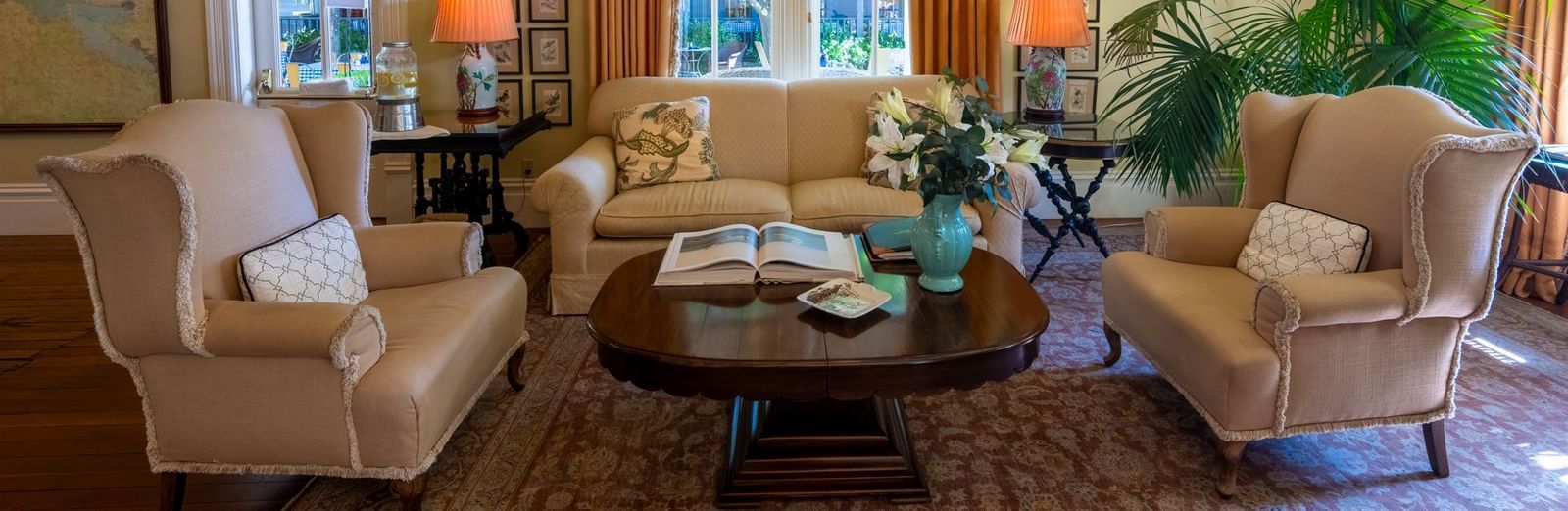 A welcoming hotel lounge with comfortable armchairs, a cozy sofa, and lush indoor plants at The Tallman Hotel.